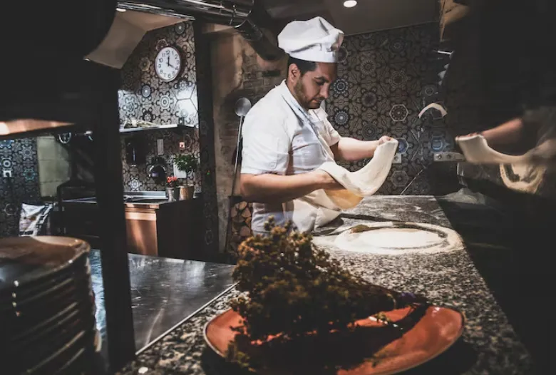 Szef kuchni przy piecu drewnianym – pizza na desce